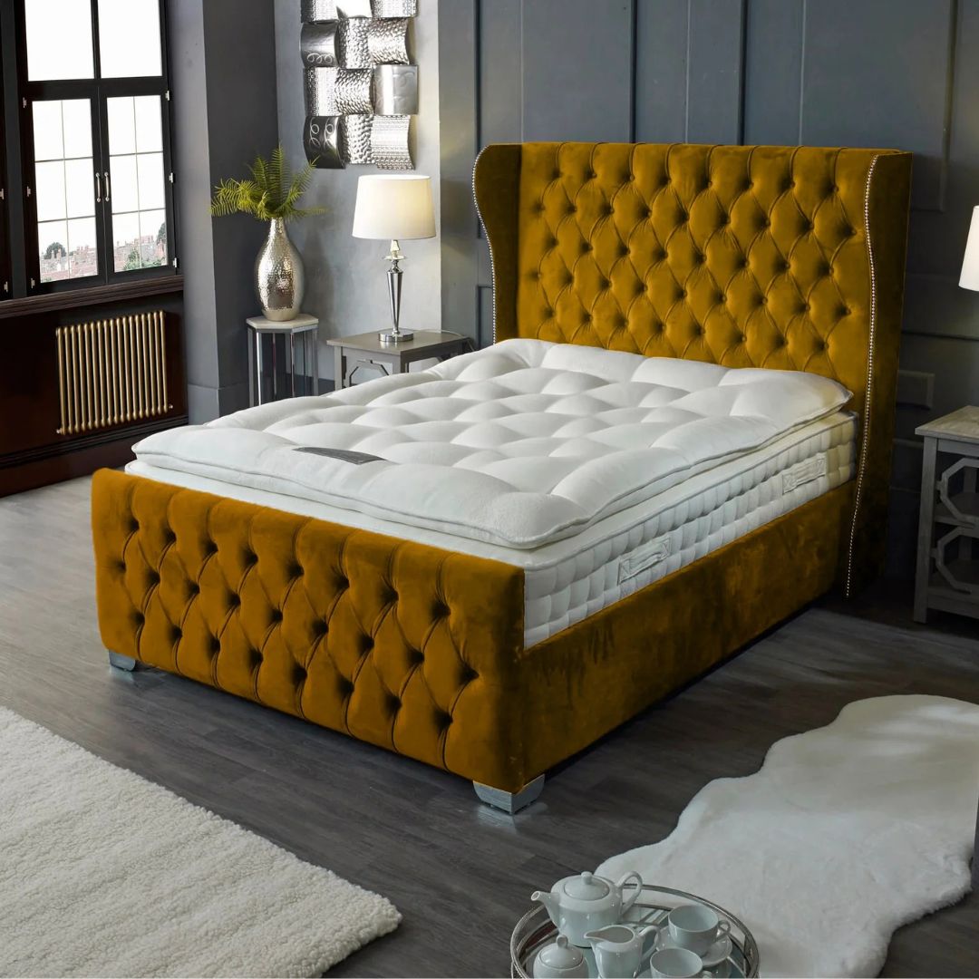Mustard yellow tufted bed in a bedroom setting with gray walls and wooden floors.