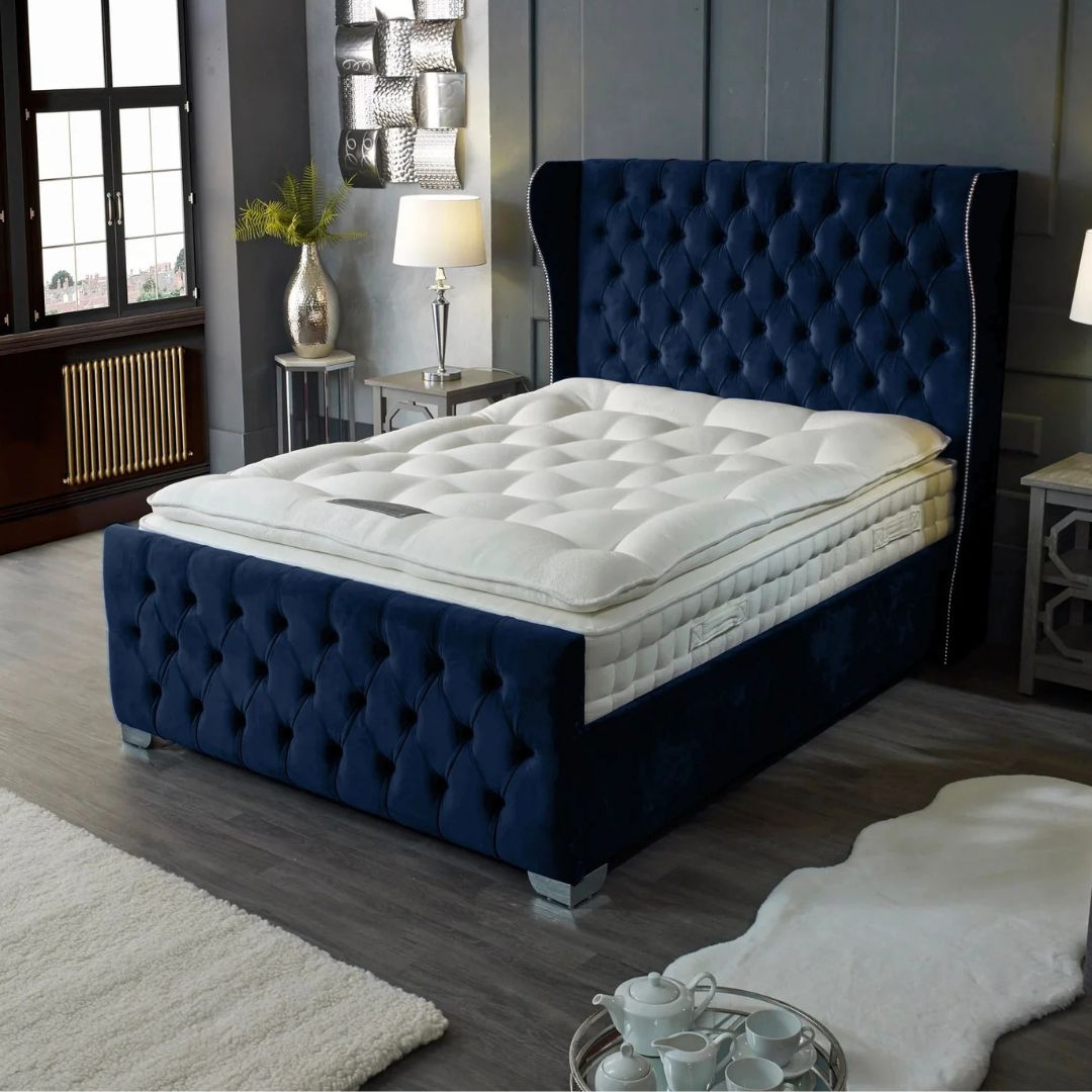 Navy blue tufted bed frame with white mattress in a bedroom setting.